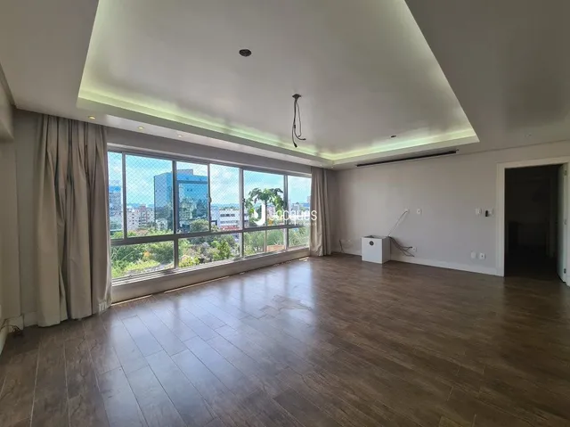 Sala de estar com piso de madeira e grandes janelas que dão vista para o exterior.