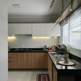 Foto de uma cozinha com armários brancos e bancadas escuras.