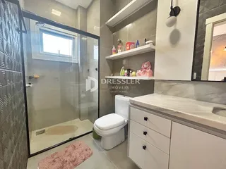 Foto de um banheiro com box de vidro e piso cerâmico.