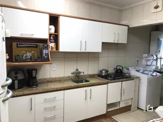 Cozinha com armários brancos e bancada de granito.