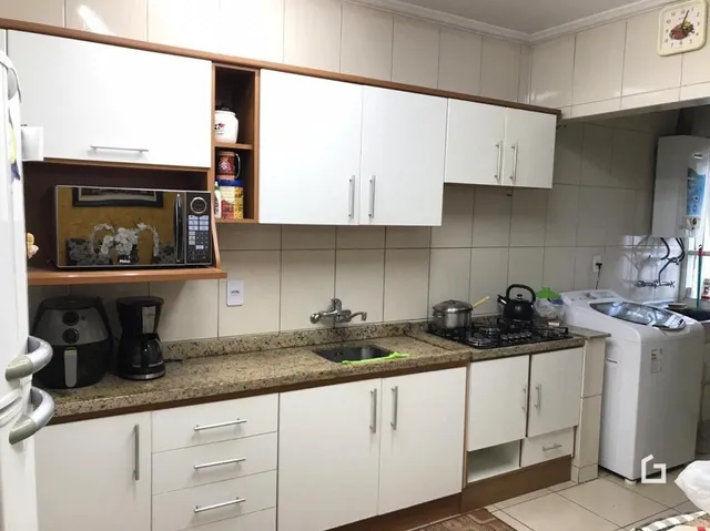 Cozinha com armários brancos e bancada de granito.
