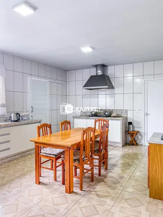 Cozinha com mesa de jantar de madeira e piso de cerâmica clara.