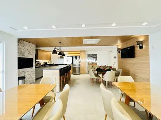 Ambiente de sala de jantar e cozinha em um apartamento moderno com detalhes em madeira e pedra.
