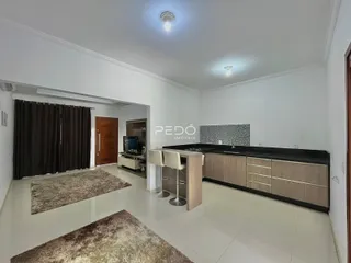 Ambiente interno de uma sala de estar com cozinha integrada e piso de cerâmica.