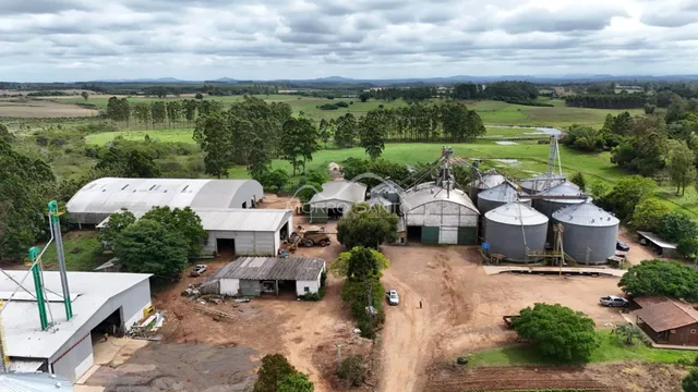 Vista aérea de uma instalação industrial com silos e campos verdes ao redor.