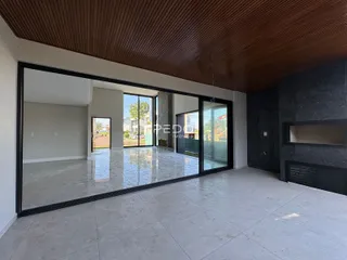 A sala de estar apresenta um piso de cerâmica claro e um teto de madeira no ambiente.