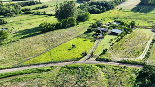 Vista aérea de uma propriedade rural com campos verdes e cercas.