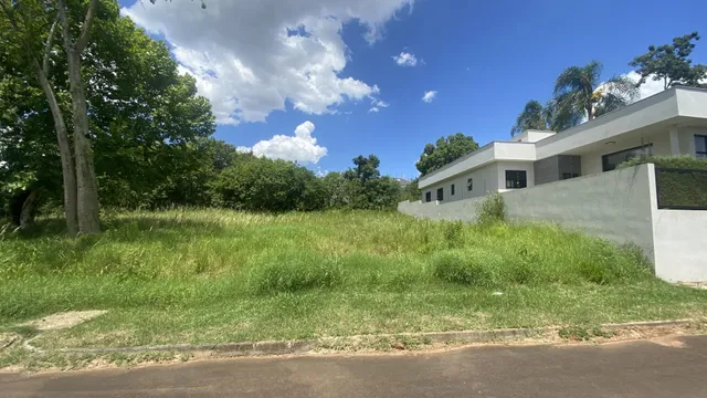 Vista externa de uma casa branca com um grande gramado verde em primeiro plano.