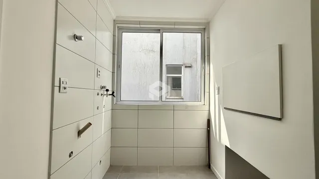 Vista interna de um corredor com paredes brancas e piso de cerâmica.