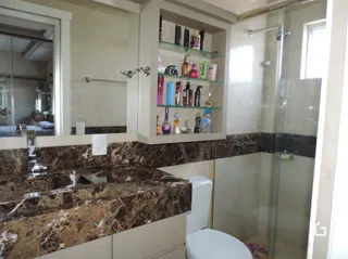 Foto de um banheiro com revestimento de mármore e box de vidro.