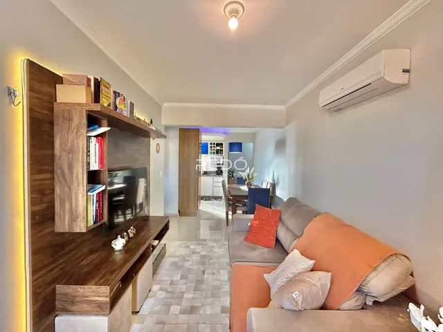 Sala de estar com sofá e estante de madeira em um apartamento em Lajeado.