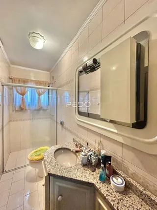 Foto de um banheiro com revestimento cerâmico e box de vidro.