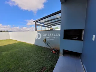 Fachada de uma residência em Lajeado, Brasil, com gramado e muro branco.