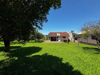 Fachada de uma casa com telhado de telhas vermelhas em um terreno com gramado.