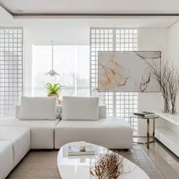 Sala de estar com sofá branco e pintura abstrata na parede.