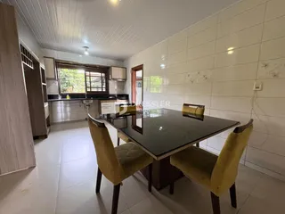 Sala de jantar com mesa de vidro e cadeiras amarelas em um imóvel em Lajeado.