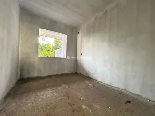 Foto de um cômodo vazio com paredes brancas e piso de concreto.