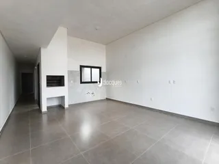 Vista interna de um ambiente amplo com paredes brancas e piso de cerâmica.