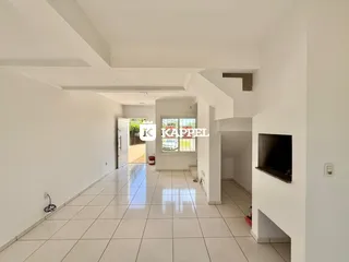 Corredor interno de uma residência com piso de cerâmica clara e paredes brancas.