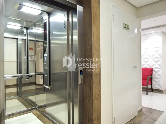 Vista interna de um corredor com portas de vidro e parede branca.