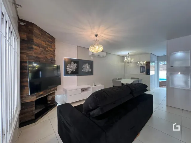 Sala de estar com sofá escuro e parede de destaque em Lajeado.