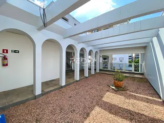 Fachada de um pátio interno com arcos brancos em uma propriedade.