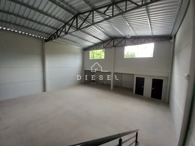Interior de um grande espaço industrial com telhado de metal.