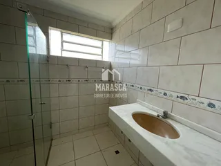 Banheiro com revestimento de cerâmica e box de vidro.