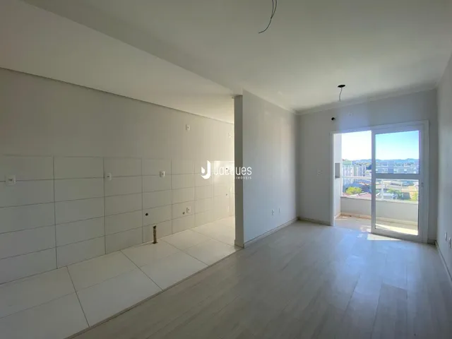 Ambiente interno de uma sala ampla com piso claro e paredes brancas.