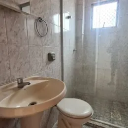 Foto de um banheiro mostrando a pia e o vaso sanitário com revestimento de azulejos.