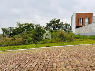 Vista externa de uma propriedade com paisagismo e pavimento de paralelepípedos.