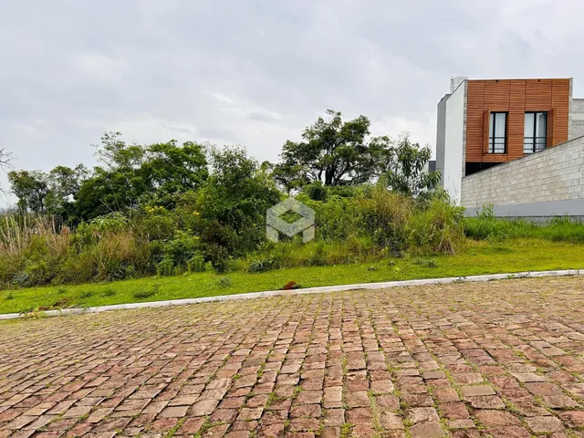 Vista externa de uma propriedade com paisagismo e pavimento de paralelepípedos.