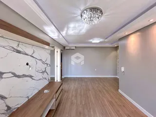 Ambiente interno de uma sala com piso de madeira clara e parede de mármore.