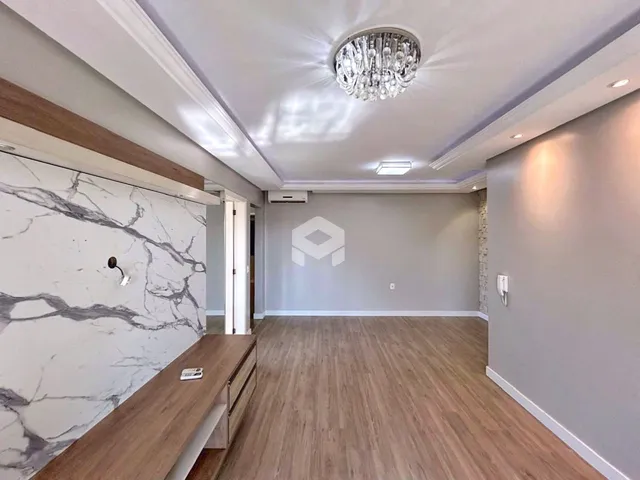 Ambiente interno de uma sala com piso de madeira clara e parede de mármore.
