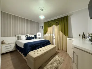 Quarto com cama de casal e móveis brancos.