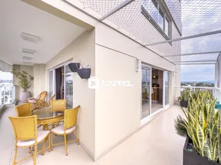Sala de jantar com mesa de vidro e cadeiras de vime em área externa.