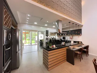 Cozinha moderna com ilha de pedra e armários escuros em um ambiente bem iluminado.