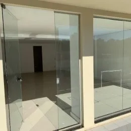 Vista interna de um corredor com divisórias de vidro em um imóvel em Lajeado.