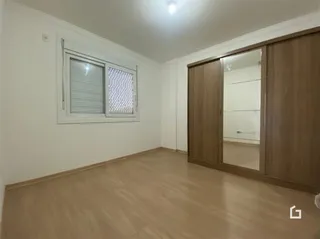 Ambiente interno de uma sala com piso de madeira clara e armário em madeira.
