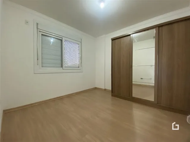 Ambiente interno de uma sala com piso de madeira clara e armário em madeira.