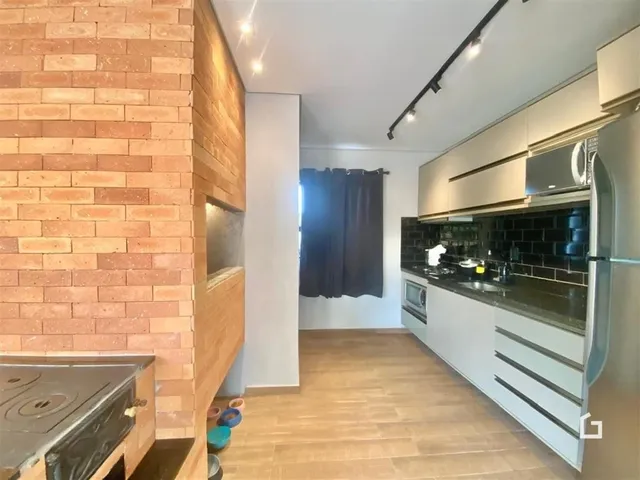 Interior de uma cozinha com parede de tijolos aparentes e armários modernos.