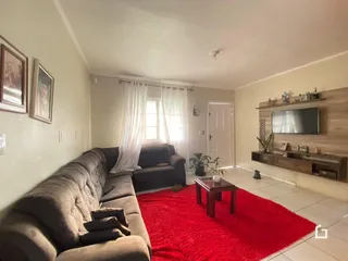 Sala de estar com sofá e tapete vermelho em um imóvel no Brasil.