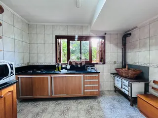 Foto de uma cozinha com armários de madeira e revestimento de azulejos brancos.