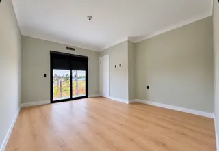Uma sala de estar com piso de madeira clara e porta de vidro que oferece vista para o exterior.