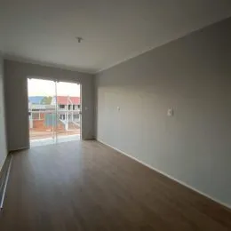 Ambiente interno com piso de madeira e porta de vidro que dá acesso ao exterior.
