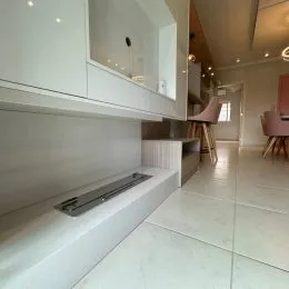 Vista de uma área de cozinha com armários brancos e piso claro.