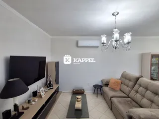Sala de estar moderna com sofá, televisão e luminária pendente.