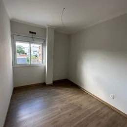 Foto interna de um cômodo com piso de madeira e janela.