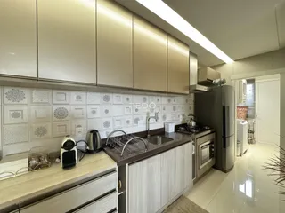 Cozinha moderna com armários e revestimentos brancos em um imóvel no Brasil.