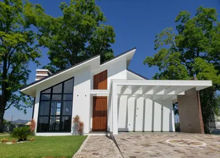 Fachada externa de uma casa moderna com grandes janelas e área coberta em Lajeado, Brasil.